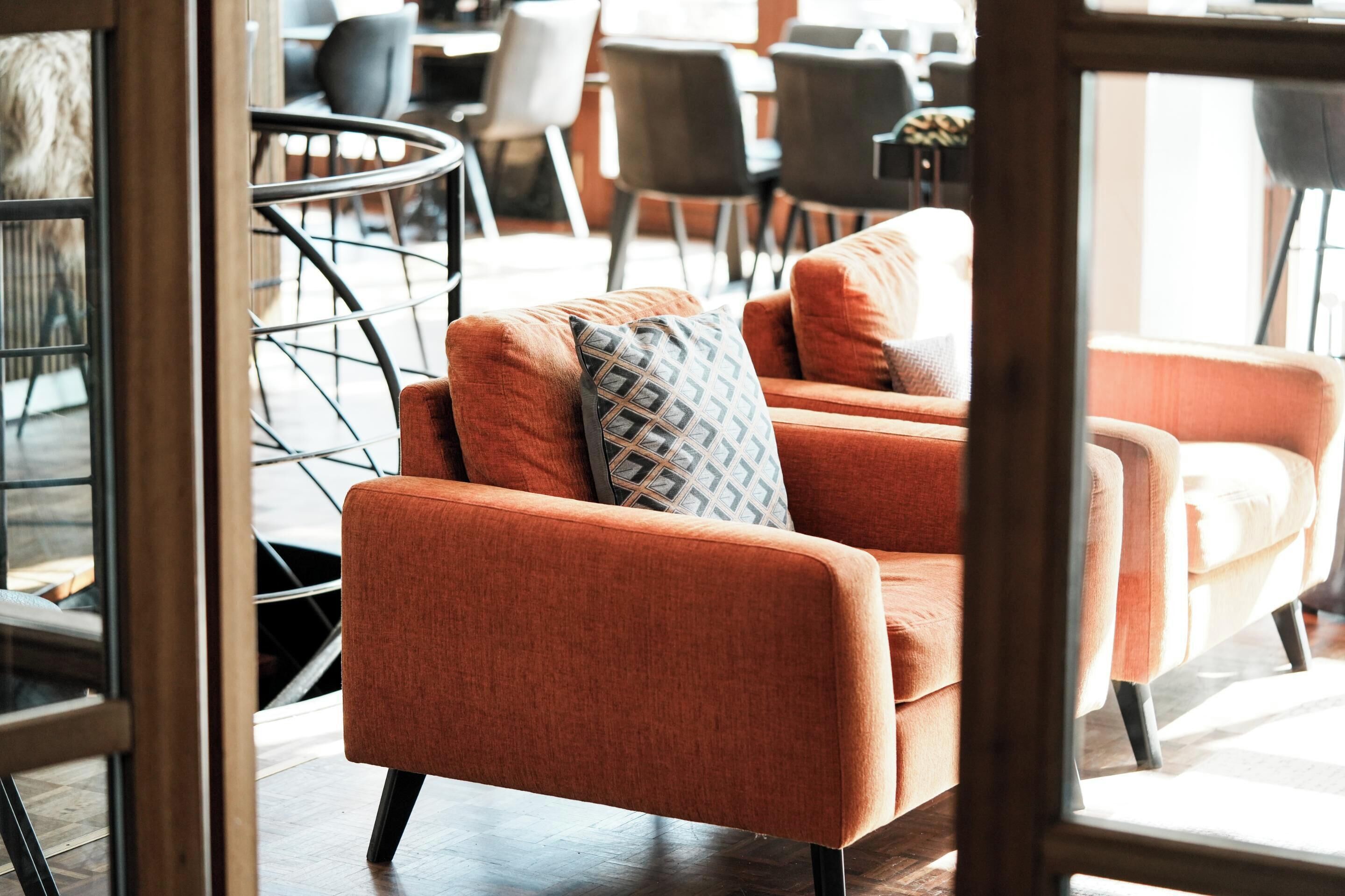 Een moderne woonkamer met een bank en stoelen, een glazen deur en uitzicht op de eetruimte.