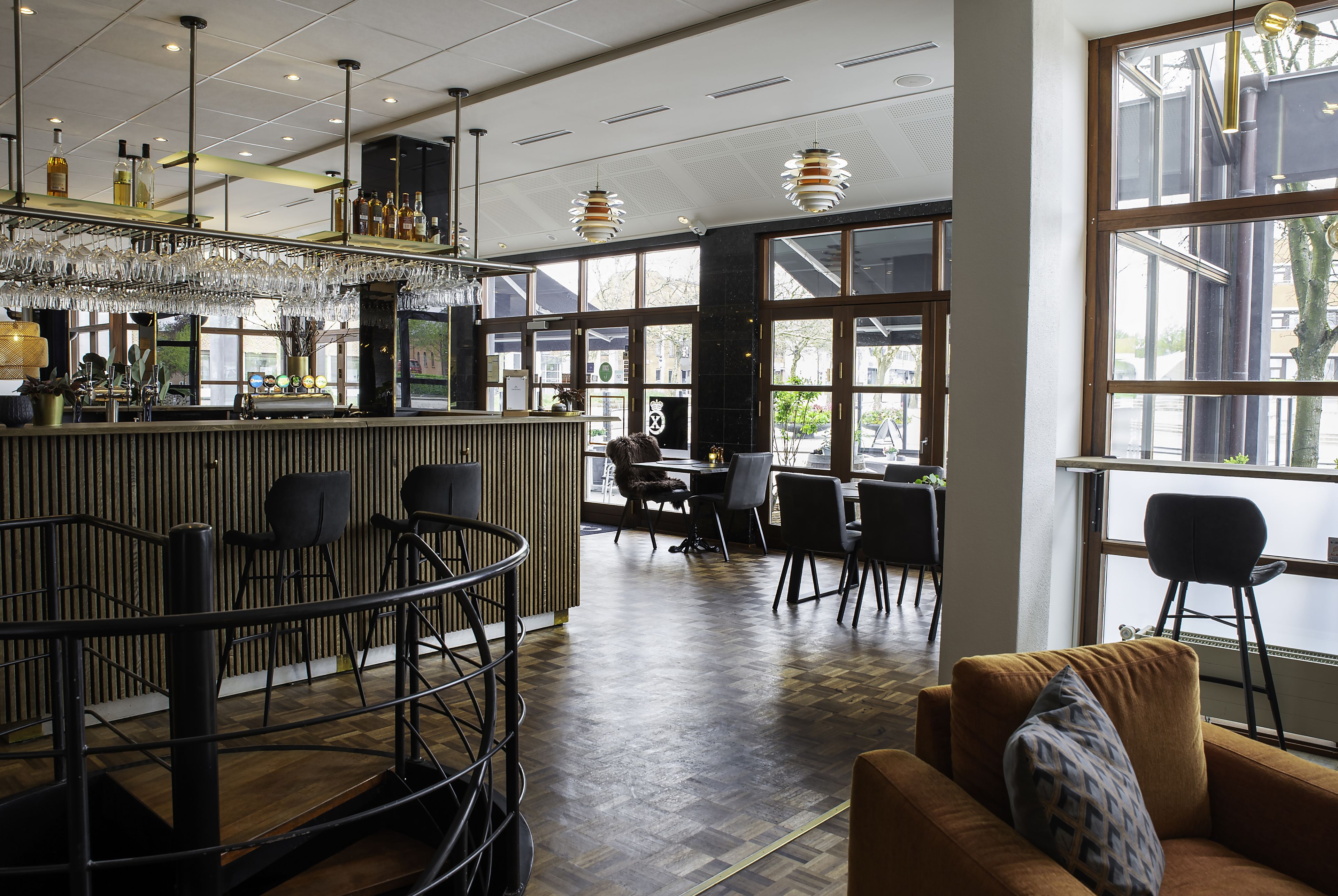 Zona de bar con mostrador, sillas y un espacio de estar con sofá y mesas de comedor.