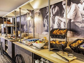 Un bufé de desayuno con diversas opciones de comida, como pasteles, frutas y bebidas, dispuesto en un mostrador de diseño moderno.