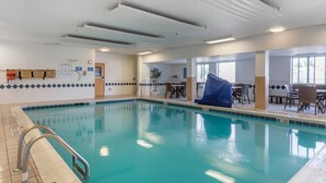 An indoor swimming pool with clear water, a changing room with lockers, and a seating area with tables and chairs. - Comfort Inn Charlotte (Charlotte)