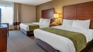 A hotel room with two beds, a desk, a lamp, and a telephone.
