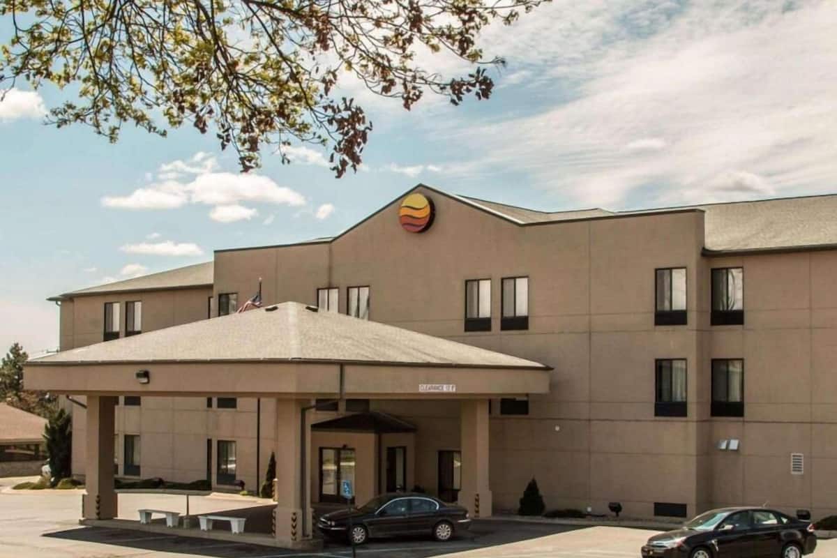 A hotel with a modern design, featuring a covered entrance, multiple windows, and a parking area.