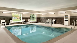 Une piscine avec des chaises blanches et un vestiaire.