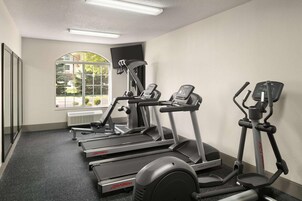 Un gimnasio con cintas de correr, una bicicleta estática y una máquina de remo.