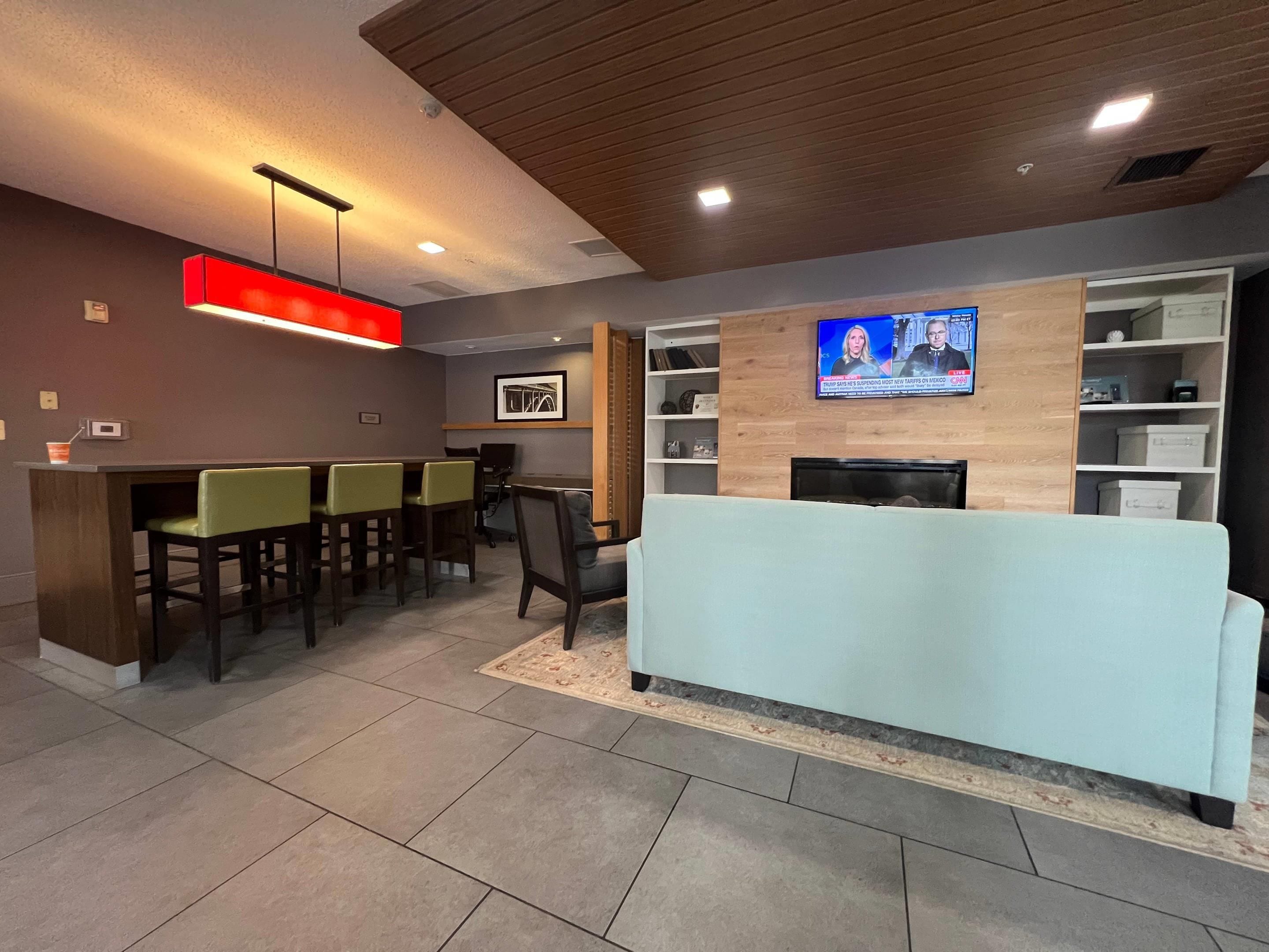 Een moderne lobby met een receptiebalie, een zithoek en een aan de muur bevestigde televisie.