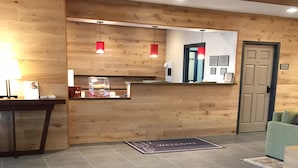 A reception area with a wooden wall, a reception desk, a welcome mat, and a door.