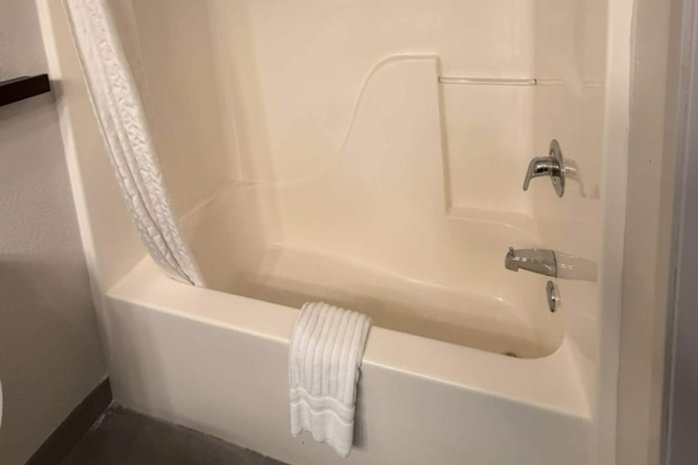 A bathtub with a towel, a shower curtain, and a faucet.