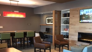 Un salon moderne doté d’une cheminée, de sièges confortables et d’un téléviseur diffusant des images d’une ville.