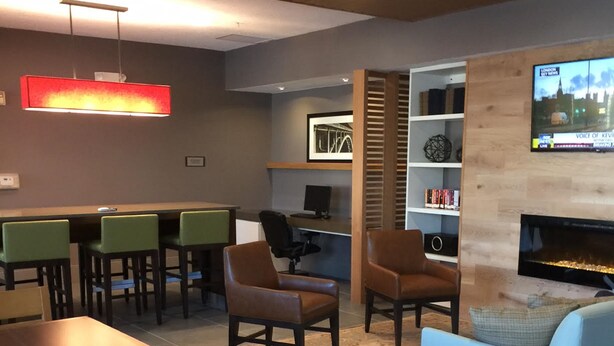 A modern lounge area with a fireplace, seating, and a television displaying a cityscape.