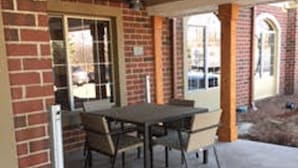 An outdoor patio area with a brick wall, a table with chairs, and a metal pole.