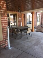 An outdoor patio area with a brick wall, a table with chairs, and a metal pole.