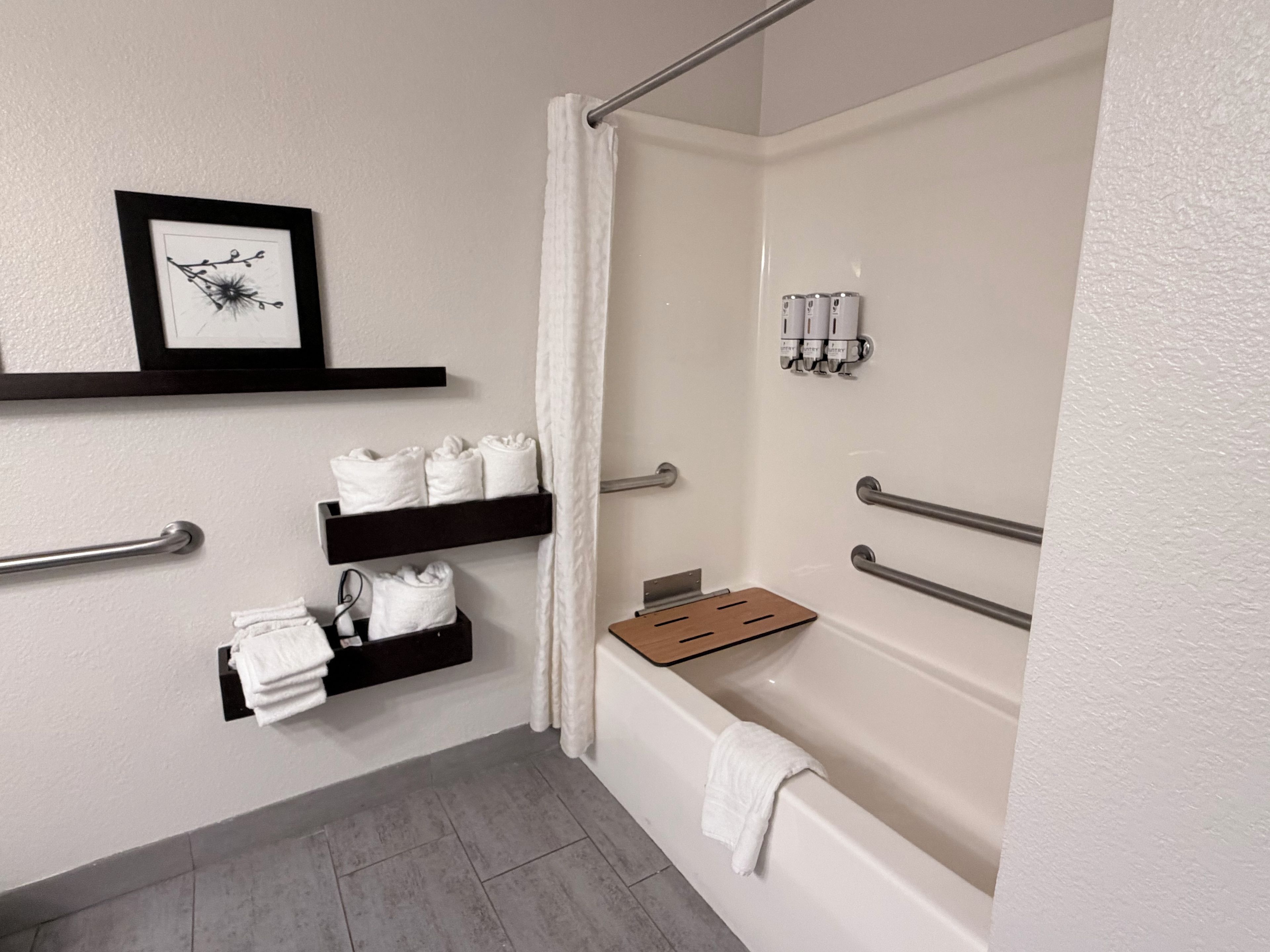 Une salle de bain avec une baignoire, une douche avec un rideau et des porte-serviettes avec des serviettes pliées.