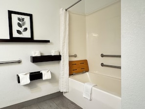 A bathroom with a bathtub, a shower curtain, towel racks, and a framed botanical print on the wall. - Country Inn & Suites by Radisson, Novi, MI (Novi)