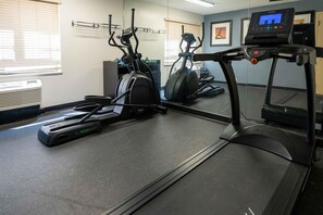 A gym with treadmills, elliptical machines, and a mirrored wall.