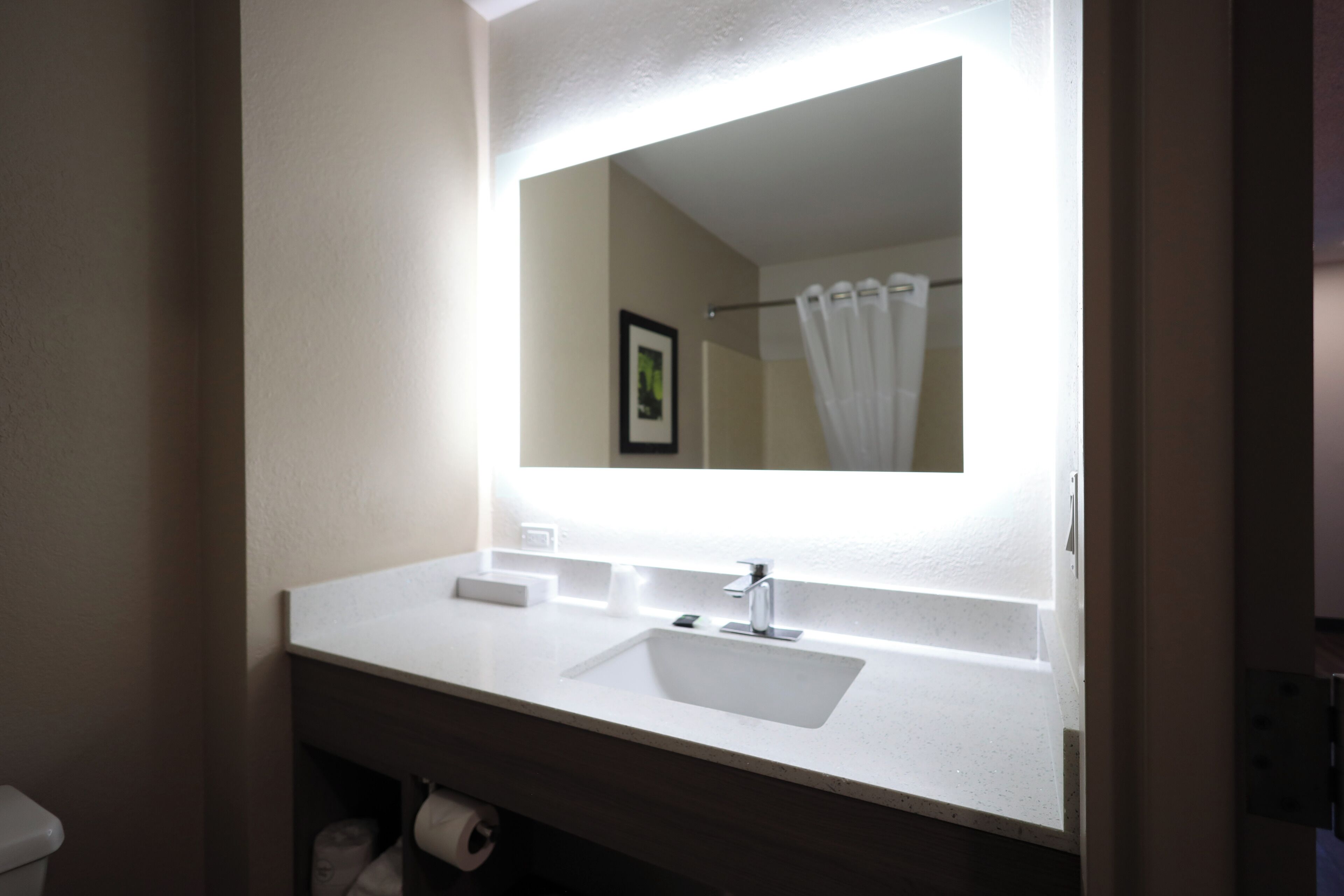 Un baño con un lavamanos blanco, un espejo y una cortina de ducha.