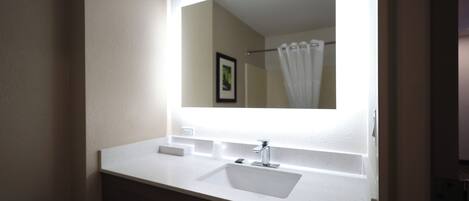 Un baño con un lavamanos blanco, un espejo y una cortina de ducha.