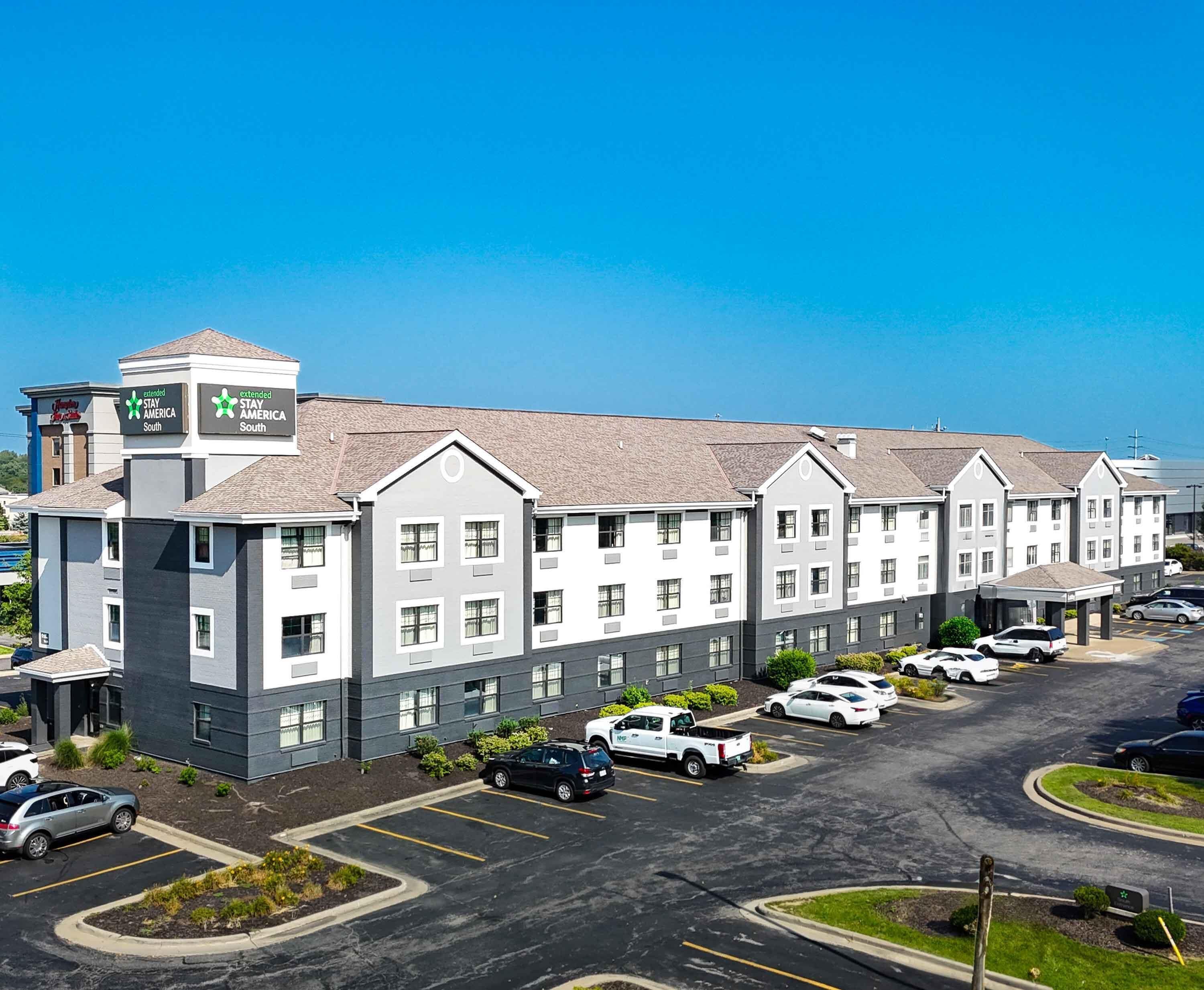 A multi-story hotel with a parking lot and a clear blue sky.