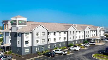 A multi-story hotel with a parking lot and a clear blue sky.