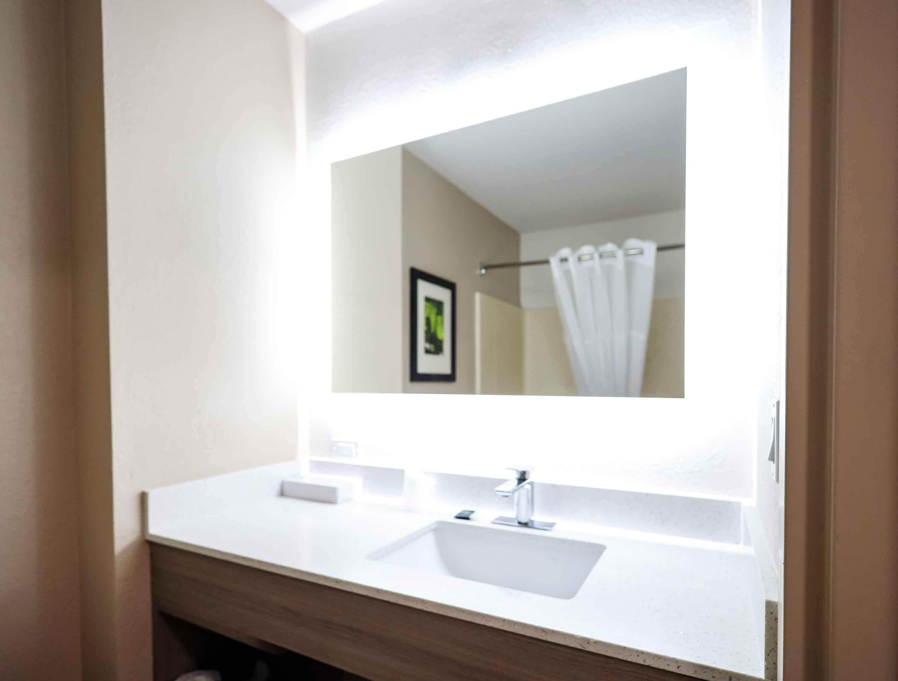 A modern bathroom with a white sink, a mirror, and a shower curtain.