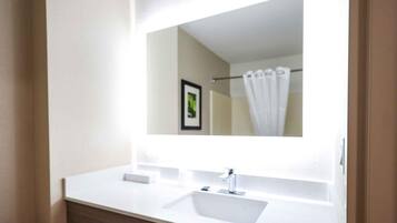 A modern bathroom with a white sink, a mirror, and a shower curtain.