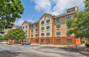 A multi-story hotel with a Stay America sign, featuring a parking lot and trees. - Extended Stay America Suites Austin Southwest (Austin)
