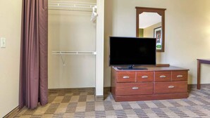 Habitación de hotel con cómoda de madera, televisor de pantalla plana, espejo y zona de ducha.