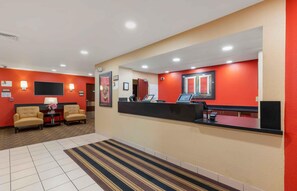 A hotel lobby with a reception desk, two sofas, a small table with a vase, and a striped carpet. - Extended Stay America Suites Austin Southwest (Austin)