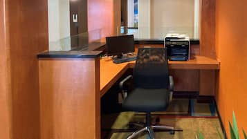 Ein moderner Arbeitsplatz mit Schreibtisch aus Holz, schwarzem Bürostuhl und einem Computerarbeitsplatz.