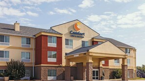 Edifício do Comfort Inn & Suites com um logotipo 'C' em destaque, várias janelas e uma área de entrada coberta.
