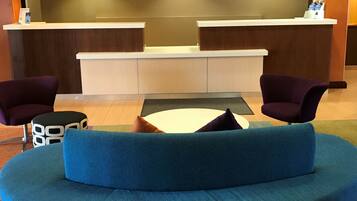 A reception area with a blue sofa, two purple armchairs, a small table, and a reception desk.