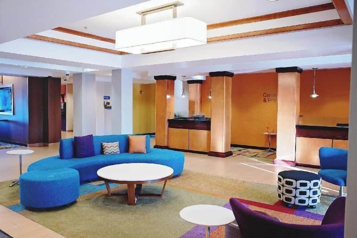 A modern lobby with a blue sofa, round tables, and a reception desk.