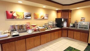 Un'area colazione in hotel con un buffet ricco di cibi e una macchina del caffè.