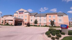 Un hotel Fairfield Inn & Suites by Marriott dotato di un ampio parcheggio e curato giardino.