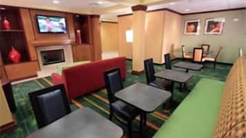 A restaurant with booths, tables, and a TV screen.