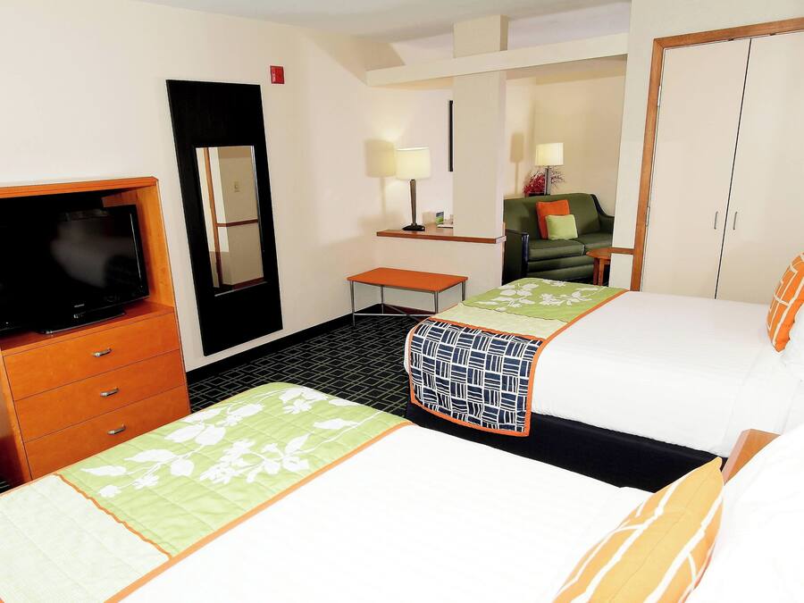 A hotel room with two beds, a TV, a mirror, a small table, and a wardrobe.
