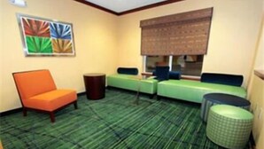 Una stanza con una moquette verde a righe, un divano verde, una poltrona arancione e un tavolino rotondo.