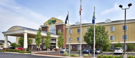 A hotel with a covered entrance, multiple flags, and a parking lot.