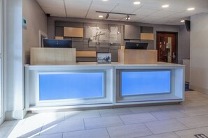 A reception desk with a modern design, featuring a logo and a digital display. - Holiday Inn Express Hotel & Suites Woodhaven by IHG (Woodhaven)