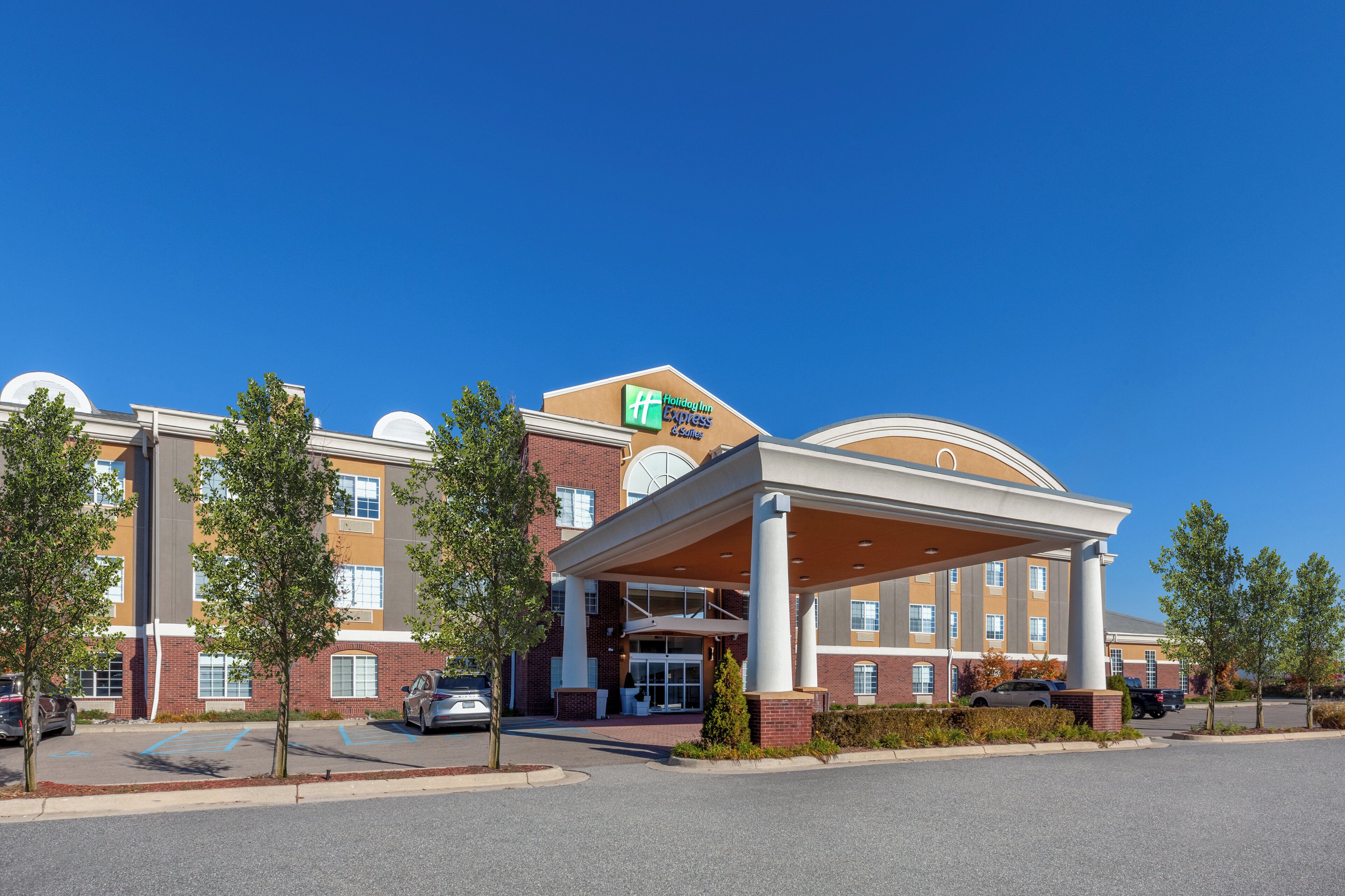 Edificio de Holiday Inn Express con entrada cubierta, fachada de ladrillo y zona de estacionamiento.