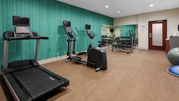 A gym with treadmills, elliptical machines, and a weight rack.