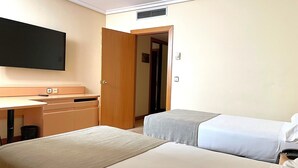 A hotel room with two beds, a desk, a television, and a door leading to another room. - Hotel AR Parquesur (Leganes)