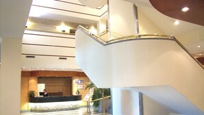 A modern hotel lobby with a reception desk, a staircase, and a second-floor balcony. - Hotel AR Parquesur (Leganes)