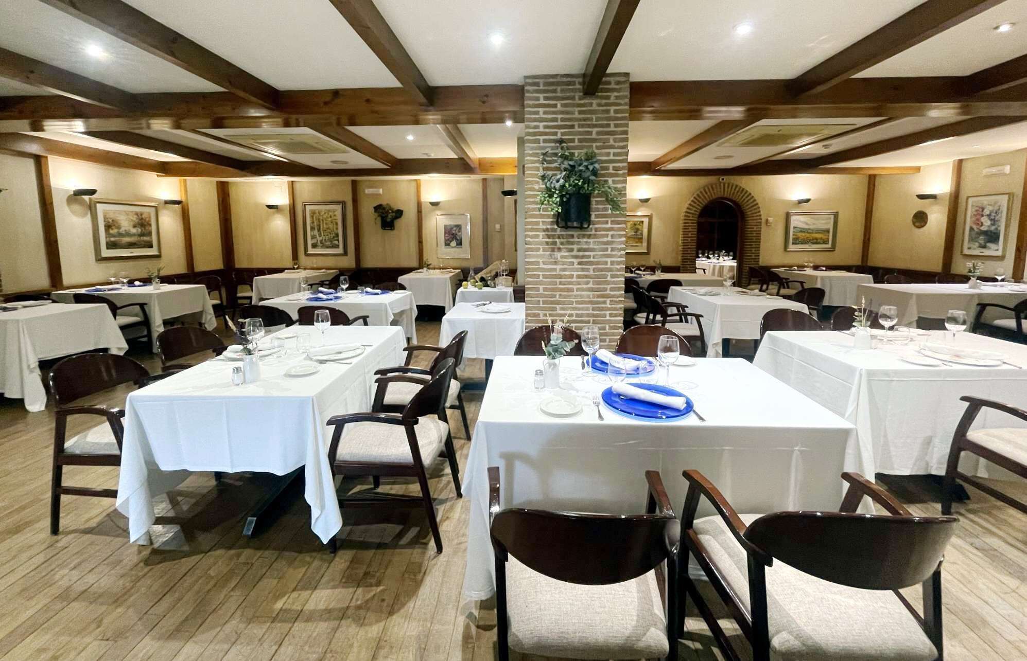 A dining area with multiple tables, chairs, and a central brick pillar.