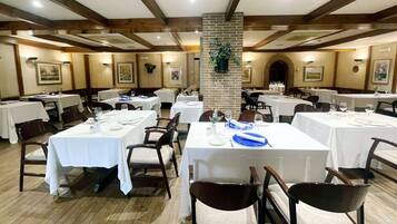 A dining area with multiple tables, chairs, and a central brick pillar.