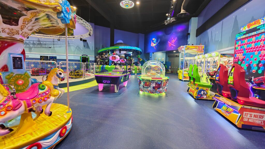 Un carrusel, máquinas de garra y juegos de arcade en un área de entretenimiento cubierta.