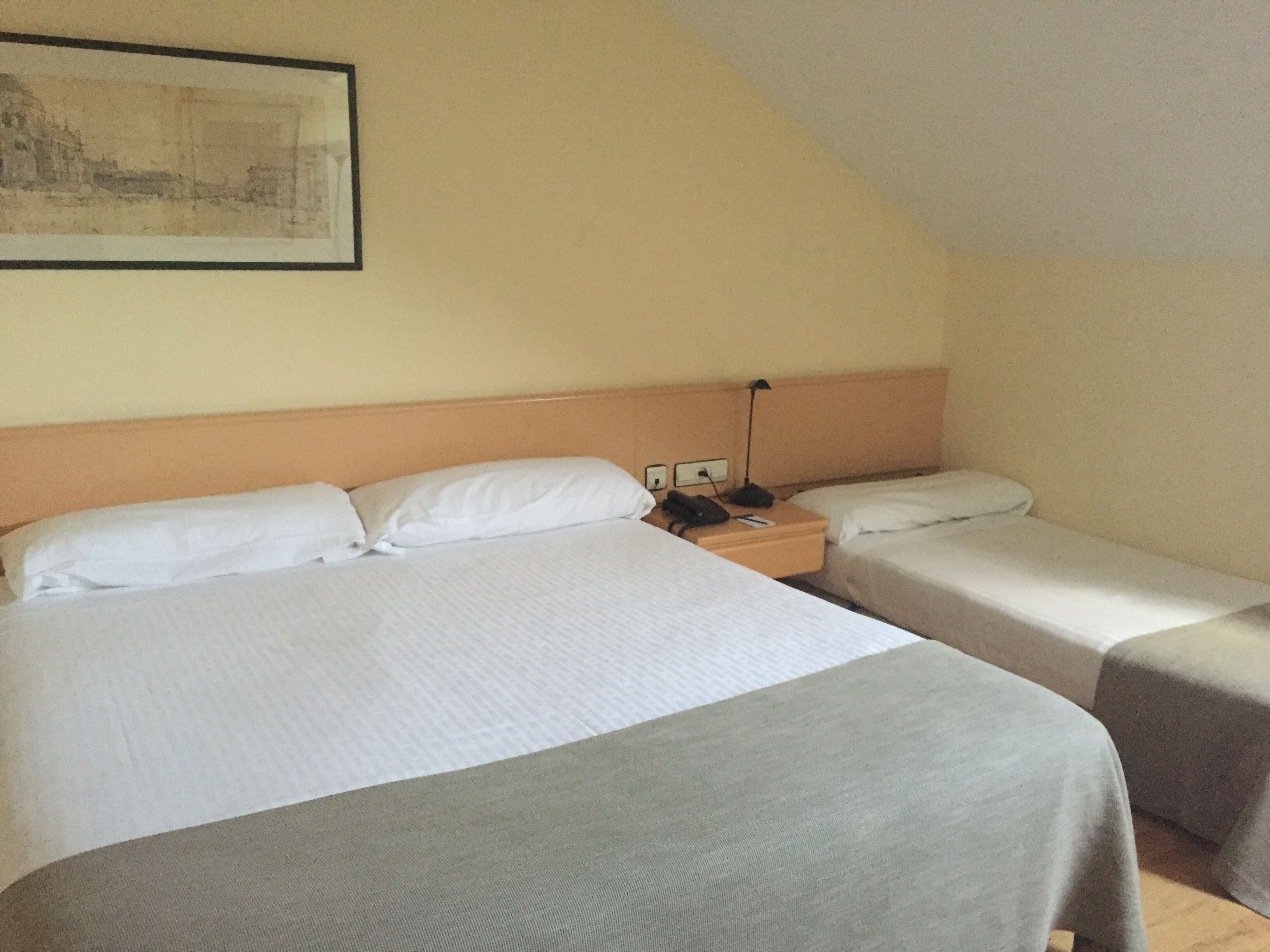 Una habitación de hotel con dos camas, una mesita de noche y una lámpara.
