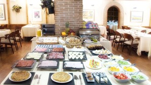 A buffet with various food items and a brick wall in the background. - Hotel AR Parquesur (Leganes)