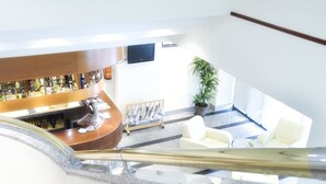 A bar area with a counter, a television mounted on the wall, and a potted plant. - Hotel AR Parquesur (Leganes)