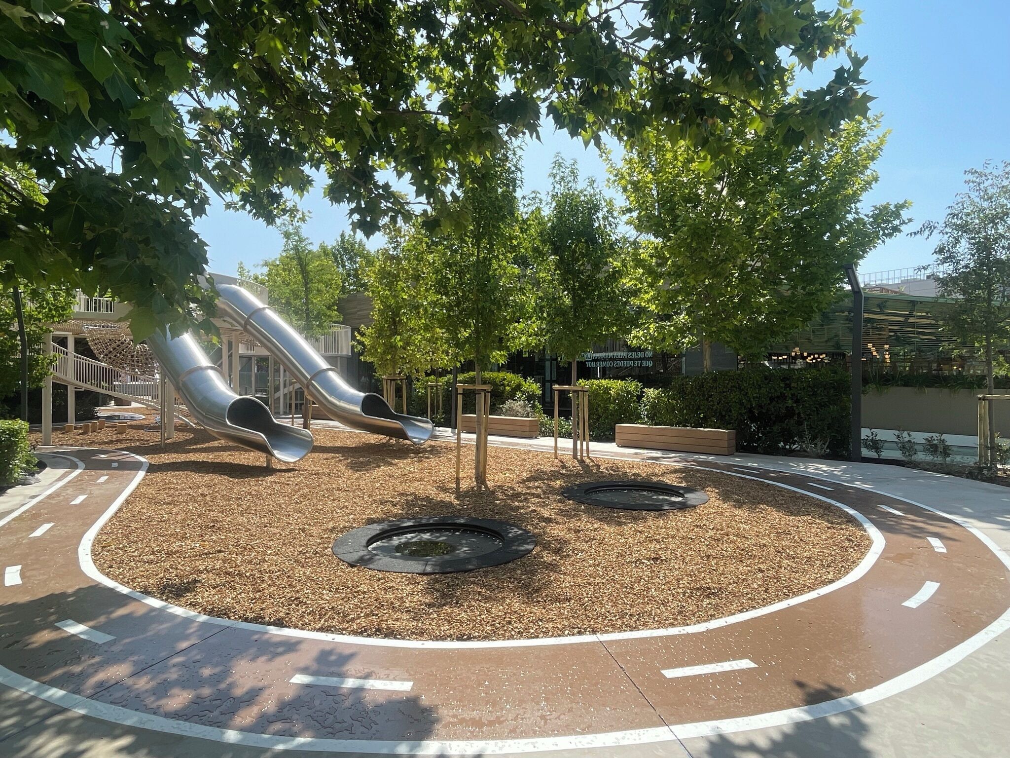 A playground with two slides and a circular paved area with mulch.