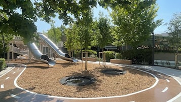 Un parque infantil con dos toboganes y una zona pavimentada circular con mantillo.